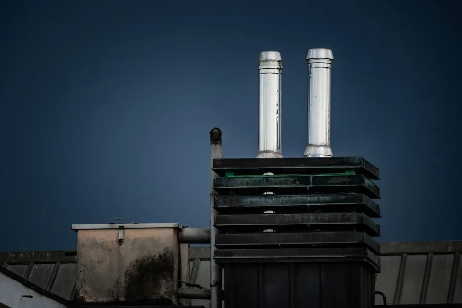 Rooftop with chimneys against a dark sky, showcasing industrial architecture.